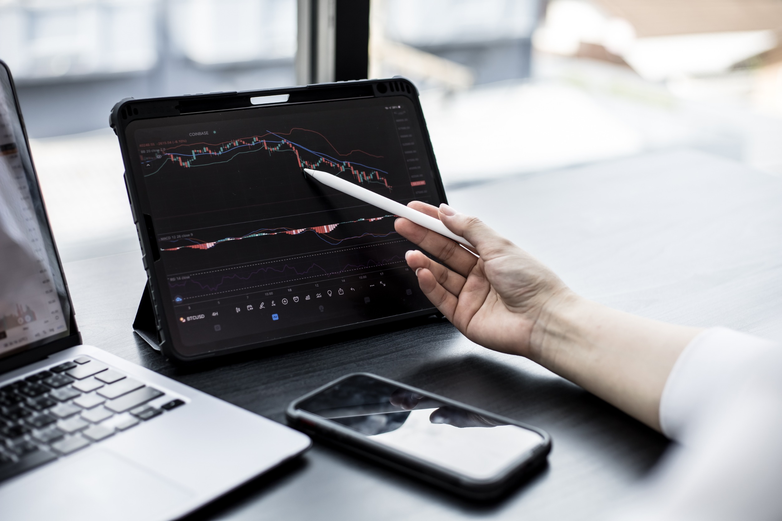 Stock investor holding a pen pointing a tablet screen that opens a stock chart program to read stock price charts, analyze purchases. Cryptocurrency stocks are popular with both new and old investors.
