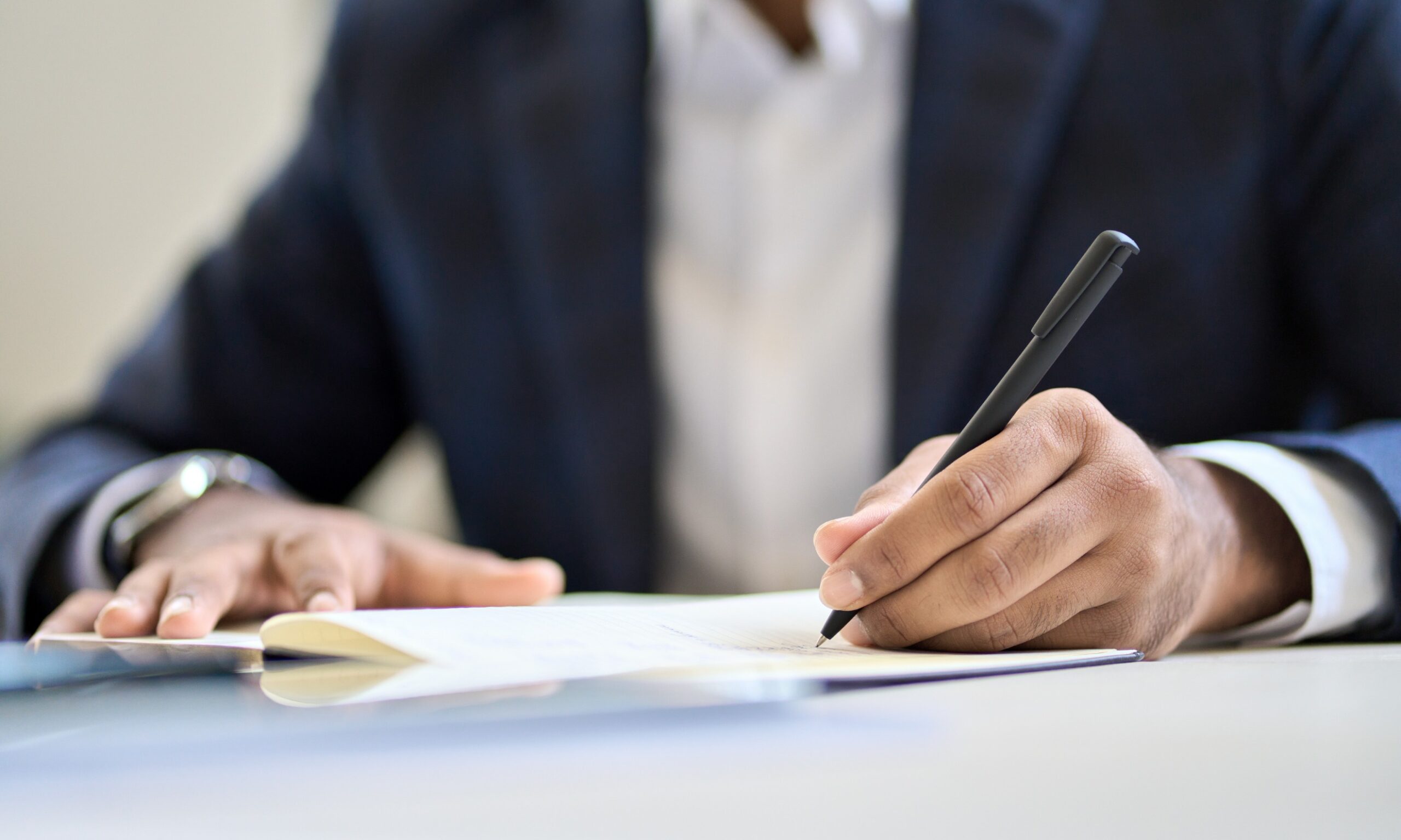 A man in a suit writing on a piece of paper.