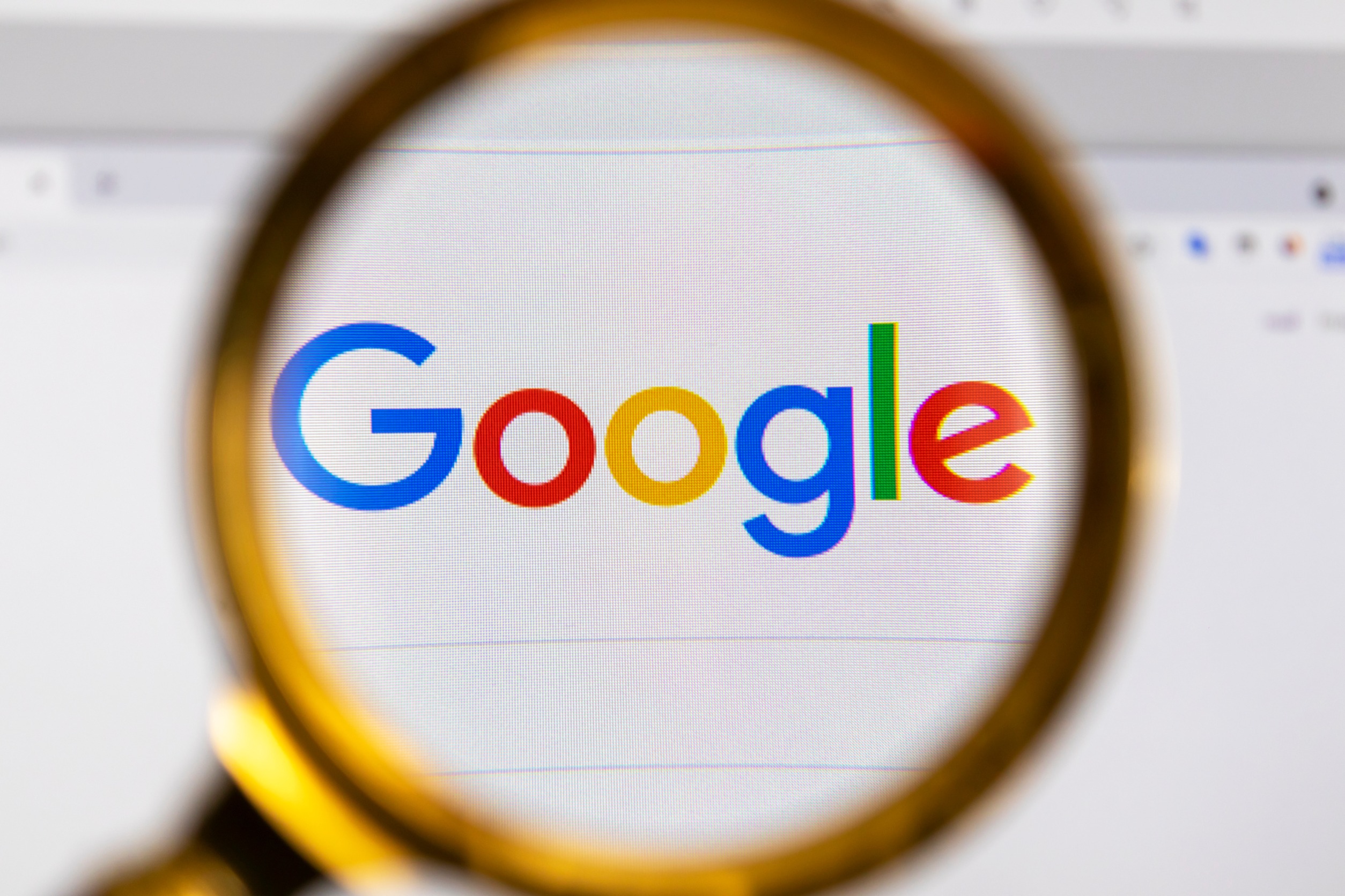 View the Google homepage through a golden magnifier, company logo. High quality photo