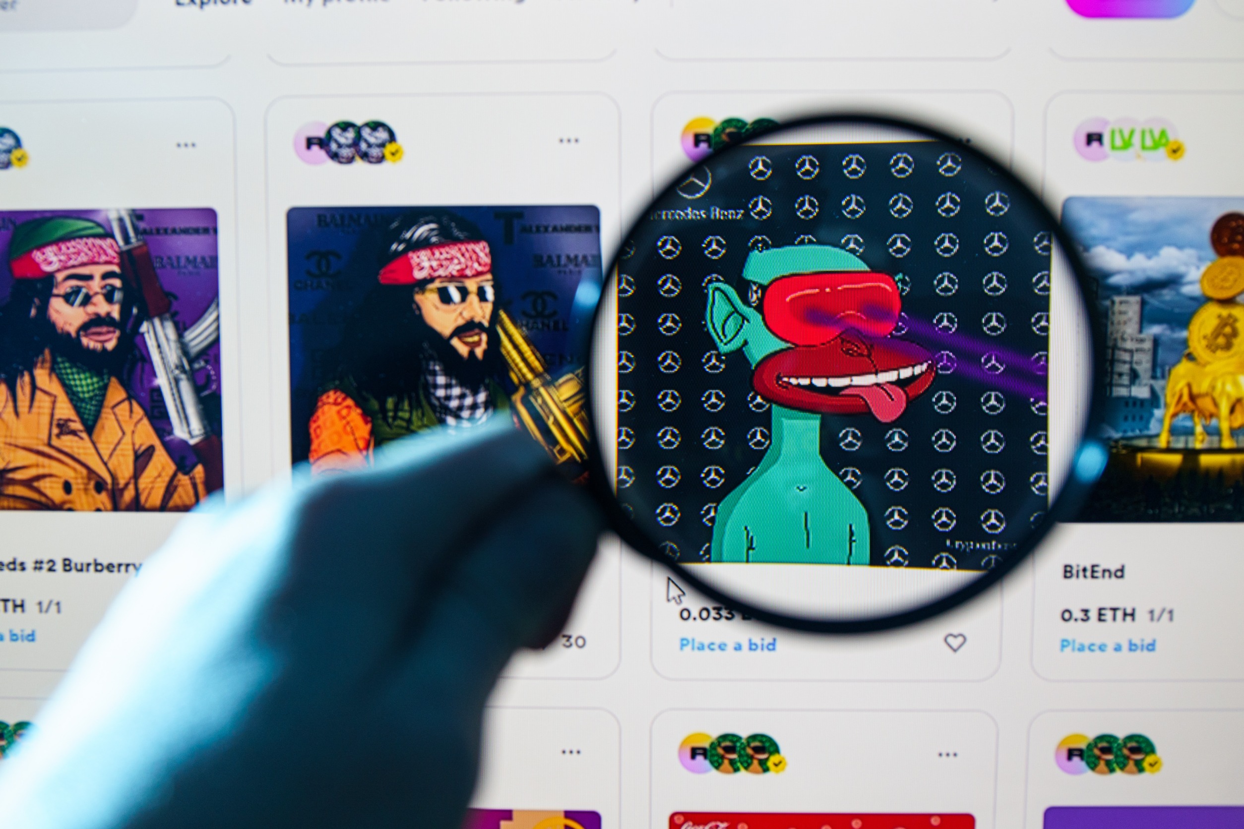 Several NFTs on a screen with one slightly zoomed under a magnifying glass.