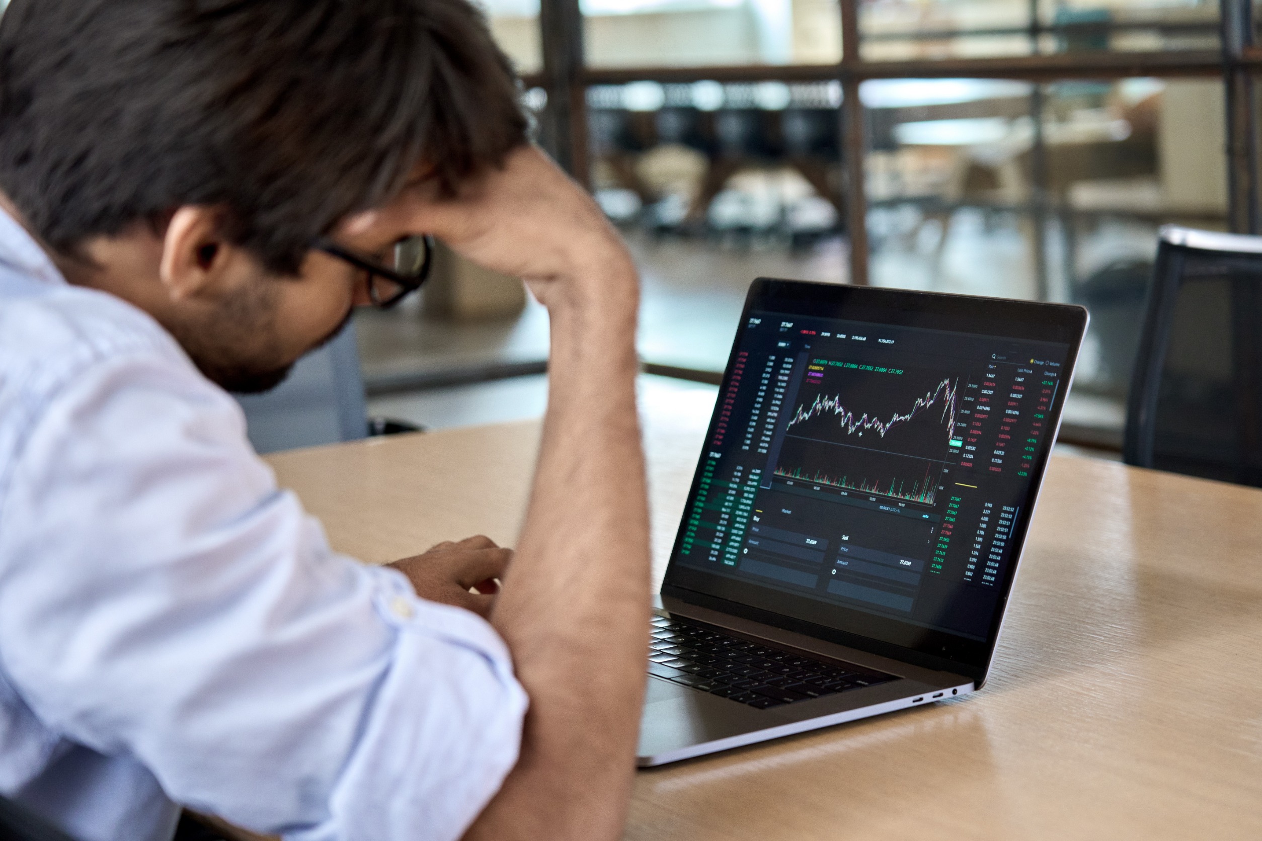 A sad investor looking at a chart on his laptop