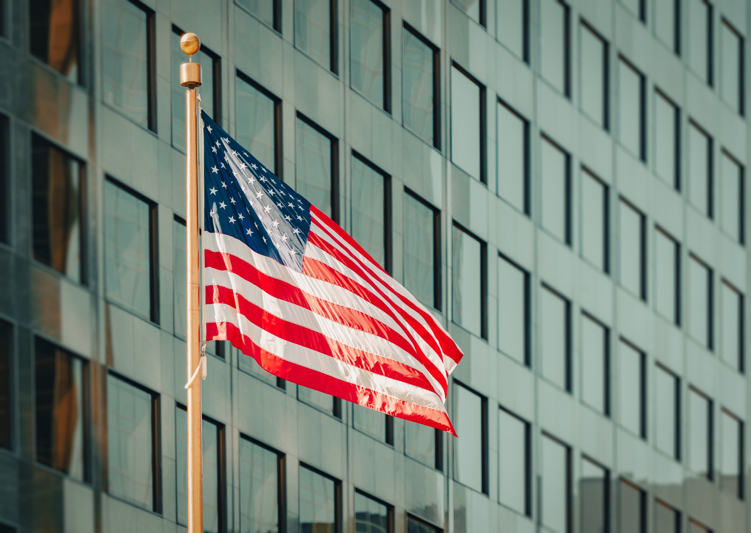 USA flag on a flagpole in front of a modern building.