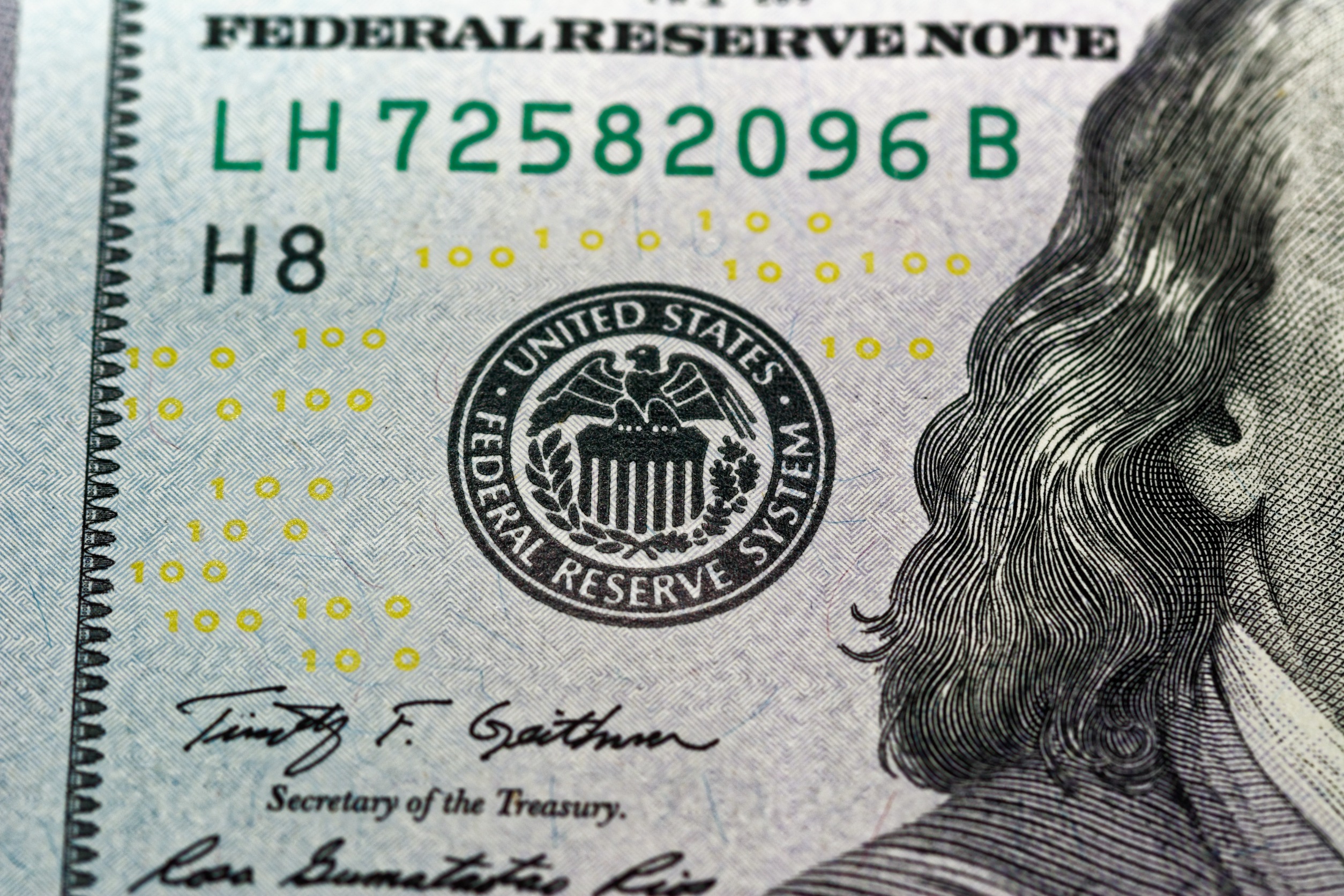 $100 USD note with a focus on the Federal Reserve system annotated on the note.