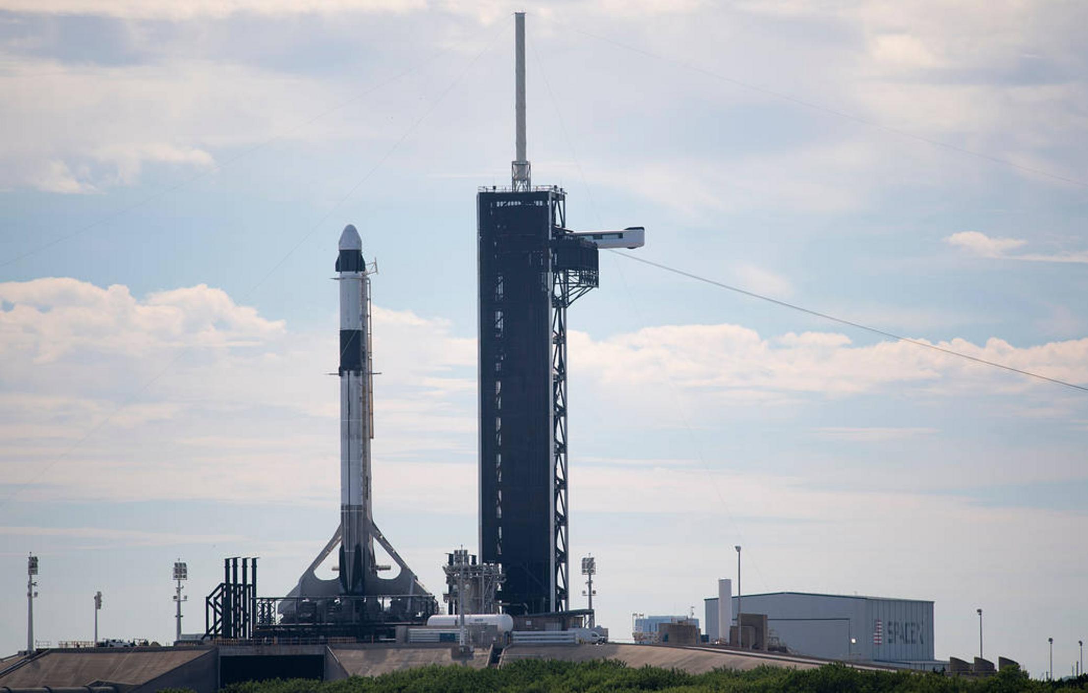 SpaceX Falcon 9 rocket on the launch pad with the launch tower in the background.